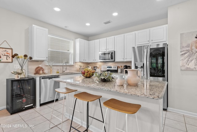 kitchen featuring white cabinets, decorative backsplash, a center island, and appliances with stainless steel finishes