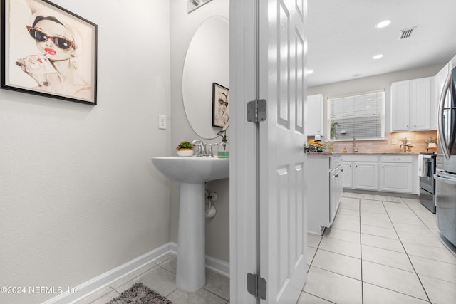 bathroom featuring tile patterned floors, double sink, and tasteful backsplash