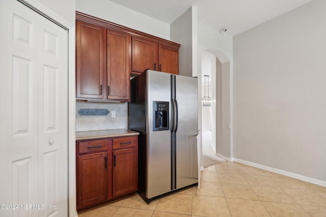 kitchen with stainless steel fridge, light tile patterned floors, a textured ceiling, and tasteful backsplash