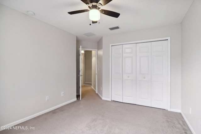 unfurnished bedroom featuring ceiling fan, light carpet, and a closet