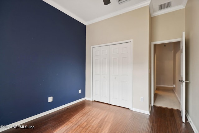 unfurnished bedroom with hardwood / wood-style flooring, ceiling fan, ornamental molding, and a closet