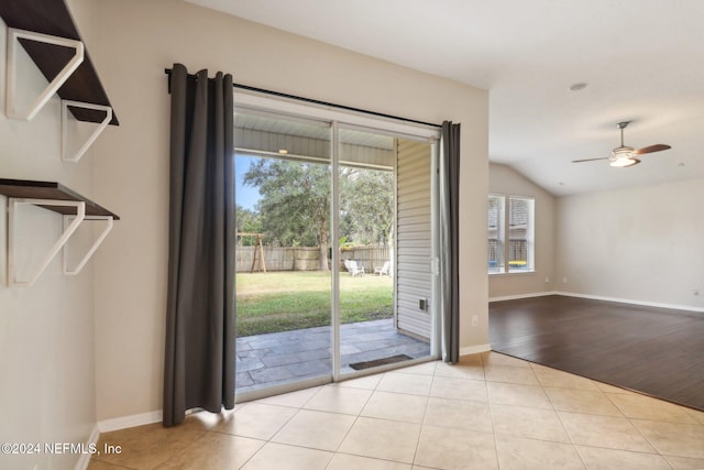 doorway featuring ceiling fan, light wood-type flooring, and lofted ceiling