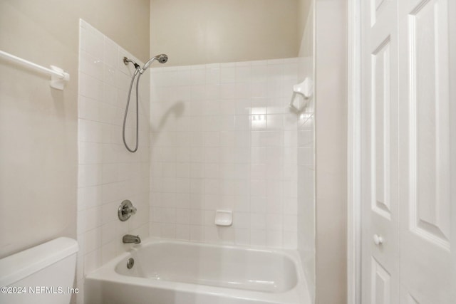 bathroom with tiled shower / bath combo and toilet