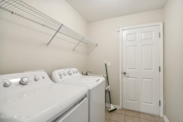 laundry room featuring washer and clothes dryer, light tile patterned flooring, and a textured ceiling