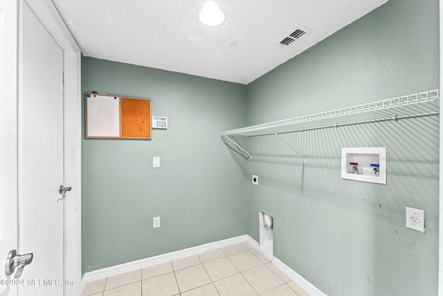 clothes washing area featuring light tile patterned floors, washer hookup, a textured ceiling, and hookup for an electric dryer