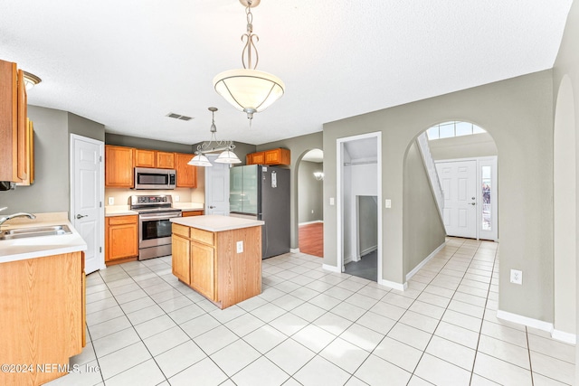 kitchen featuring sink, a center island, decorative light fixtures, light tile patterned flooring, and appliances with stainless steel finishes