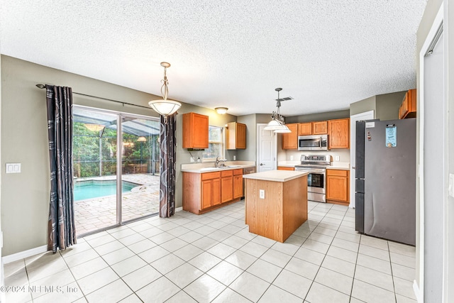 kitchen with pendant lighting, a center island, sink, light tile patterned flooring, and stainless steel appliances