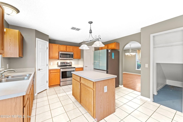 kitchen with sink, stainless steel appliances, an inviting chandelier, decorative light fixtures, and a kitchen island