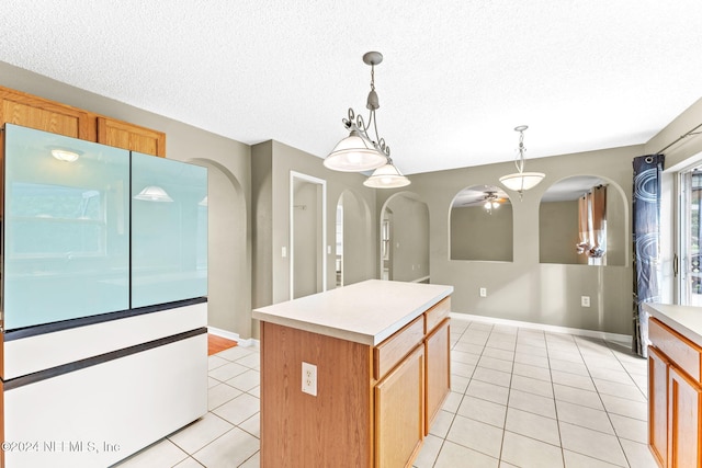 kitchen featuring a textured ceiling, a kitchen island, pendant lighting, and light tile patterned floors