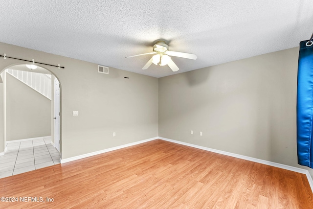 spare room featuring ceiling fan, light wood-type flooring, and a textured ceiling