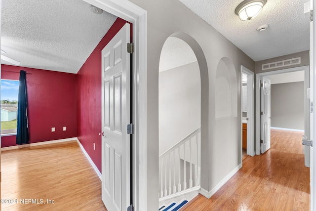 hallway with hardwood / wood-style floors and a textured ceiling