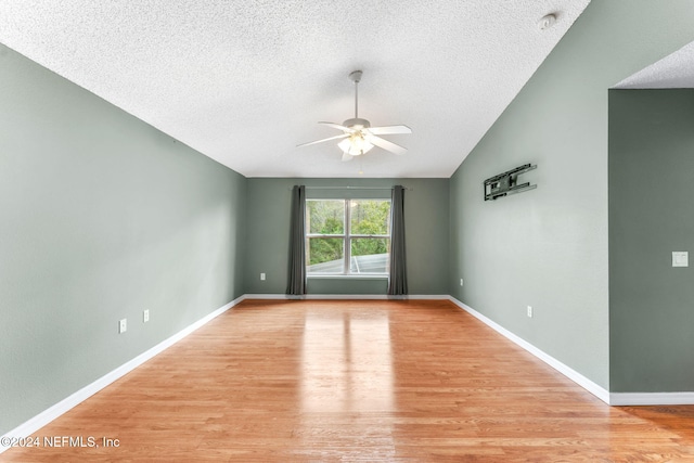 unfurnished room with vaulted ceiling, ceiling fan, light hardwood / wood-style floors, and a textured ceiling