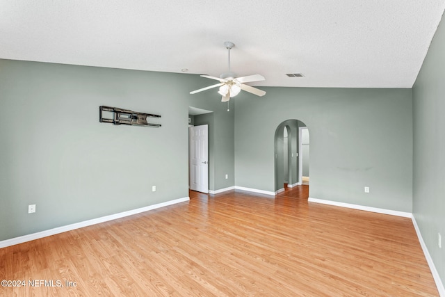 empty room featuring a textured ceiling, vaulted ceiling, light hardwood / wood-style flooring, and ceiling fan