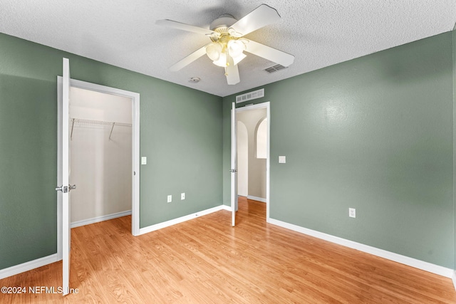 unfurnished bedroom with ceiling fan, light hardwood / wood-style floors, a textured ceiling, and a closet