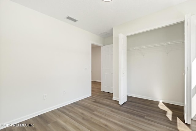 unfurnished bedroom featuring dark hardwood / wood-style floors and a closet