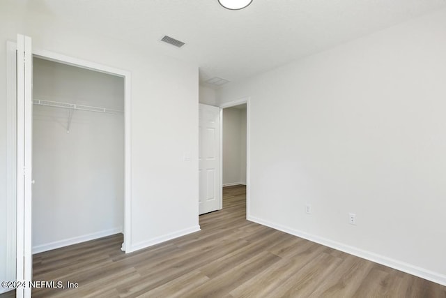 unfurnished bedroom featuring wood-type flooring and a closet