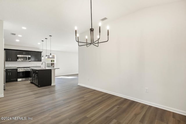 kitchen featuring appliances with stainless steel finishes, dark hardwood / wood-style flooring, pendant lighting, a center island with sink, and a chandelier