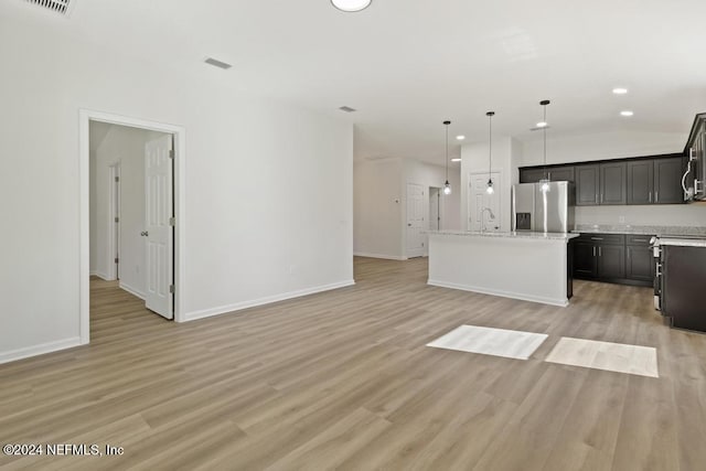 kitchen with light stone countertops, light wood-type flooring, decorative light fixtures, a kitchen island, and stainless steel fridge with ice dispenser