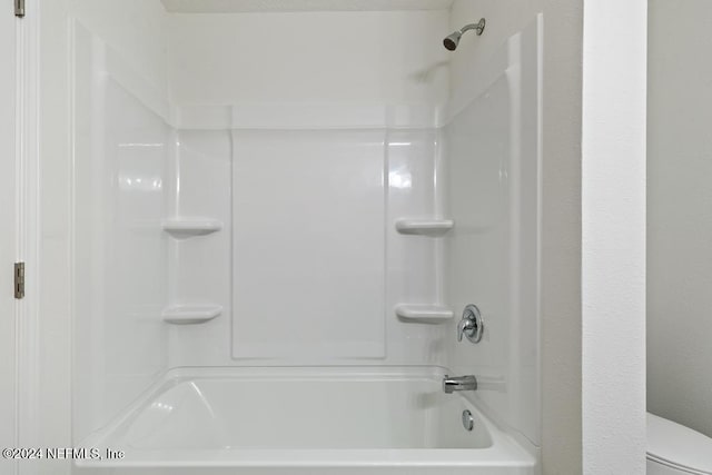 bathroom with washtub / shower combination and toilet