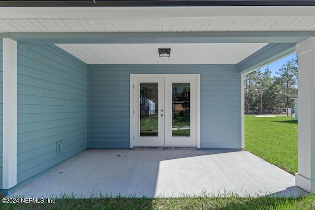 entrance to property featuring a yard, french doors, and a patio