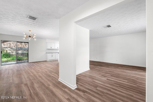 unfurnished living room with dark hardwood / wood-style flooring, a chandelier, and a textured ceiling