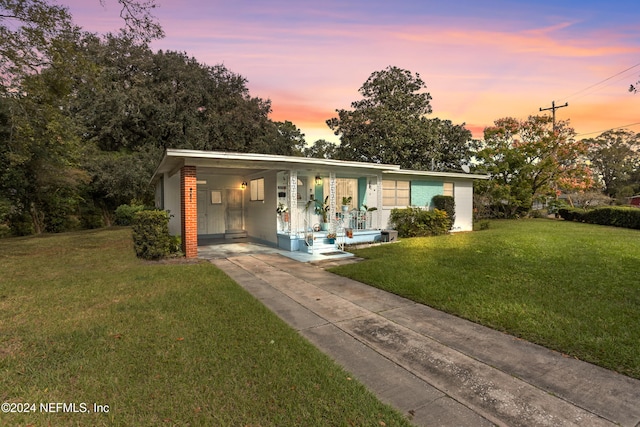 view of front of property featuring a lawn and a carport