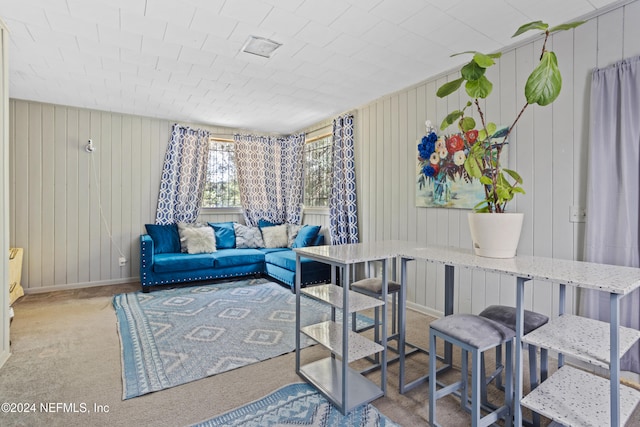 carpeted living room with wood walls