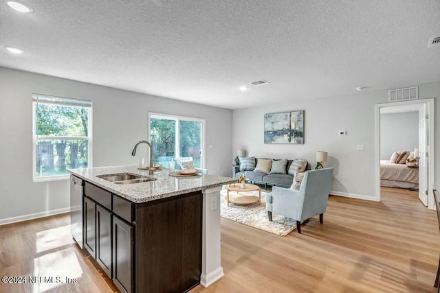 kitchen with a textured ceiling, dark brown cabinetry, sink, dishwasher, and light hardwood / wood-style floors