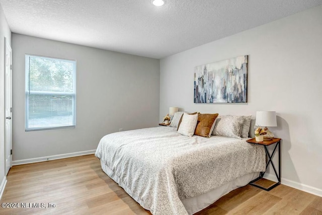 bedroom with a textured ceiling and light wood-type flooring