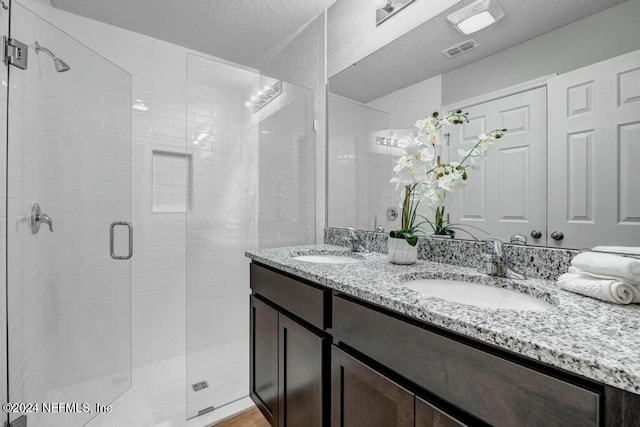 bathroom with vanity, an enclosed shower, and a textured ceiling