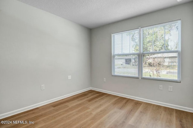 unfurnished room with light wood-type flooring, a textured ceiling, and a wealth of natural light