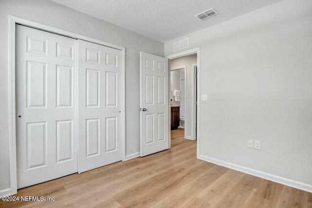 unfurnished bedroom featuring a closet, a textured ceiling, and light wood-type flooring