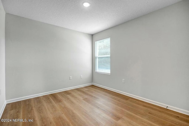 unfurnished room featuring a textured ceiling and light hardwood / wood-style flooring