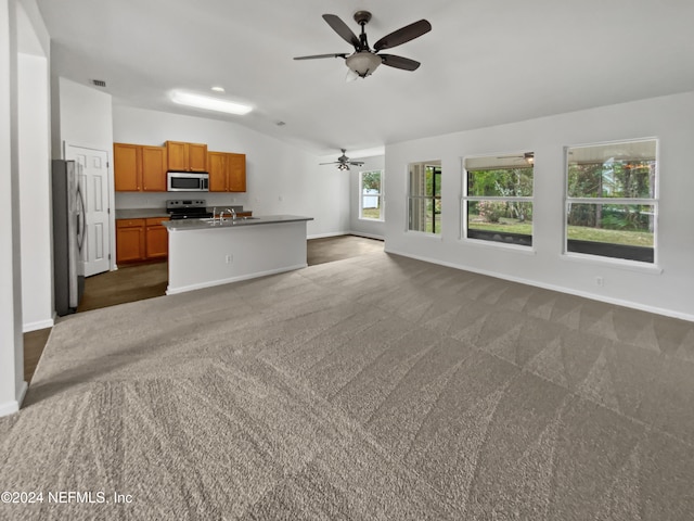 unfurnished living room with ceiling fan, dark carpet, sink, and vaulted ceiling