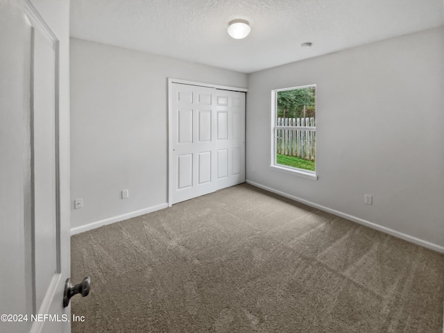 unfurnished bedroom featuring a closet, carpet, and a textured ceiling