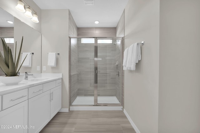 bathroom featuring hardwood / wood-style floors, vanity, and a shower with door