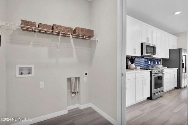 kitchen featuring decorative backsplash, white cabinetry, and stainless steel appliances