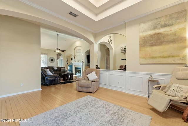 living area with a tray ceiling, ceiling fan, hardwood / wood-style floors, and ornamental molding