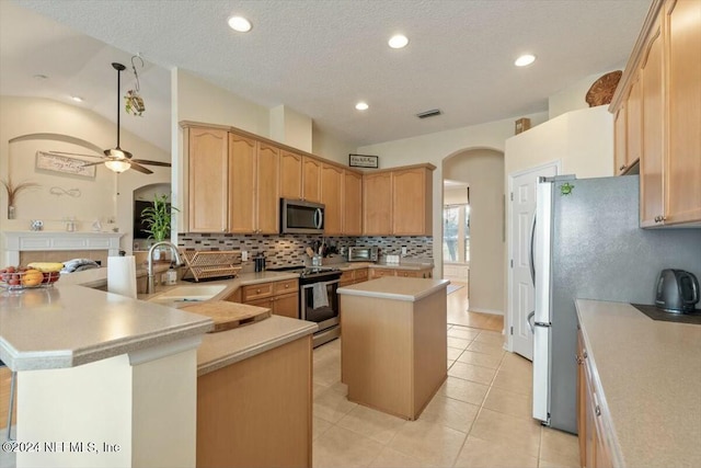 kitchen featuring ceiling fan, stainless steel appliances, a kitchen island, kitchen peninsula, and light tile patterned flooring