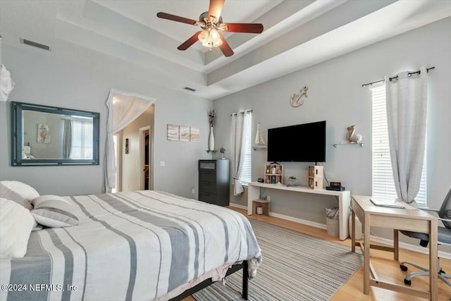 bedroom with a tray ceiling, ceiling fan, and hardwood / wood-style flooring