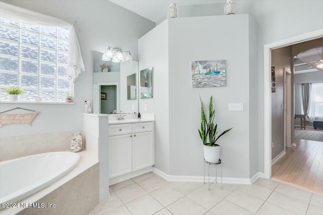 bathroom featuring tile patterned flooring, vanity, and tiled tub