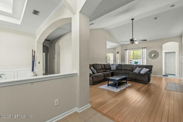living room featuring a textured ceiling, arched walkways, ceiling fan, visible vents, and wood finished floors