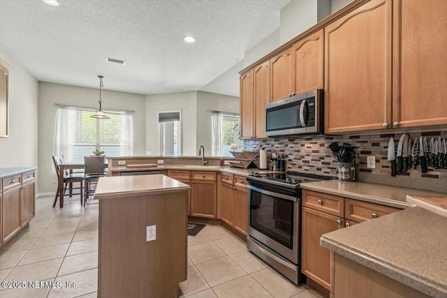 kitchen featuring light tile patterned floors, backsplash, a kitchen island, visible vents, and appliances with stainless steel finishes