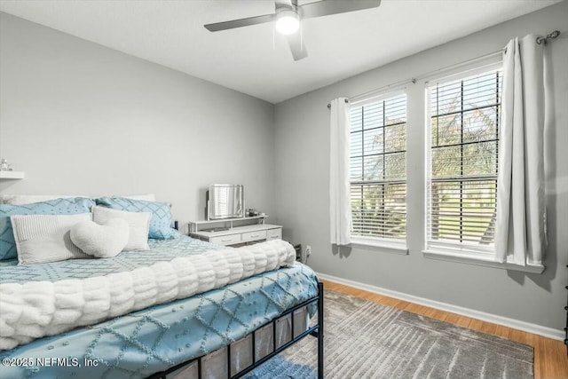 bedroom featuring baseboards, wood finished floors, and a ceiling fan