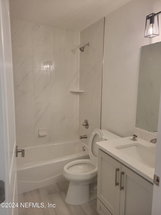 full bathroom with vanity, tiled shower / bath combo, a textured ceiling, hardwood / wood-style floors, and toilet