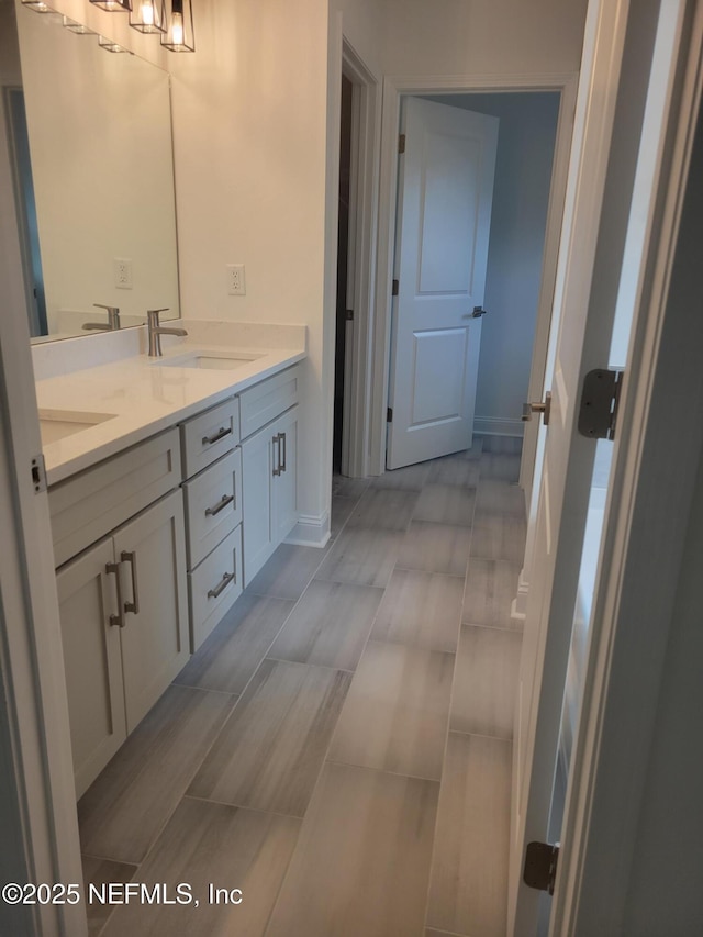 bathroom with double vanity, baseboards, and a sink