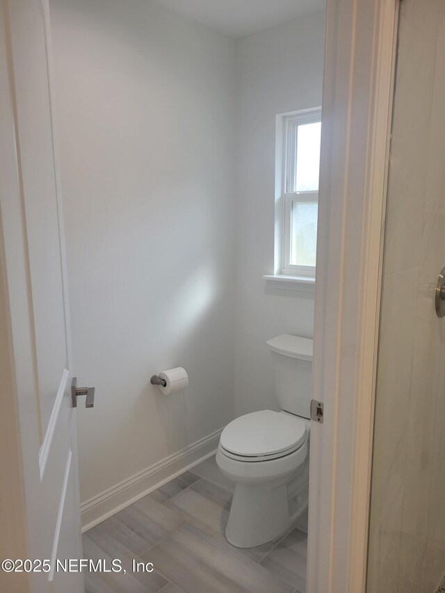 bathroom featuring toilet, wood finished floors, and baseboards