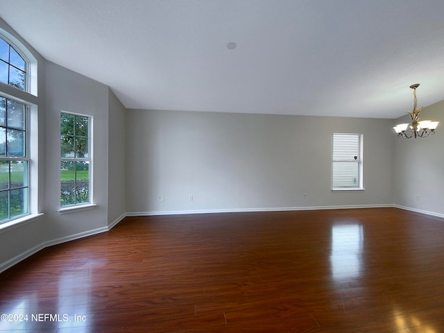 unfurnished room featuring a notable chandelier, lofted ceiling, and dark wood-type flooring