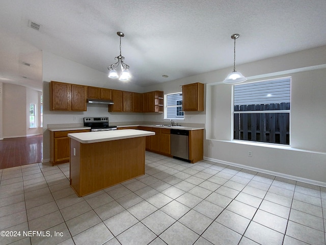 kitchen featuring appliances with stainless steel finishes, vaulted ceiling, light tile patterned floors, a center island, and hanging light fixtures