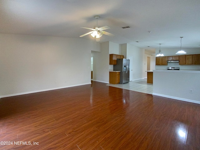 unfurnished living room featuring ceiling fan with notable chandelier and light wood-type flooring